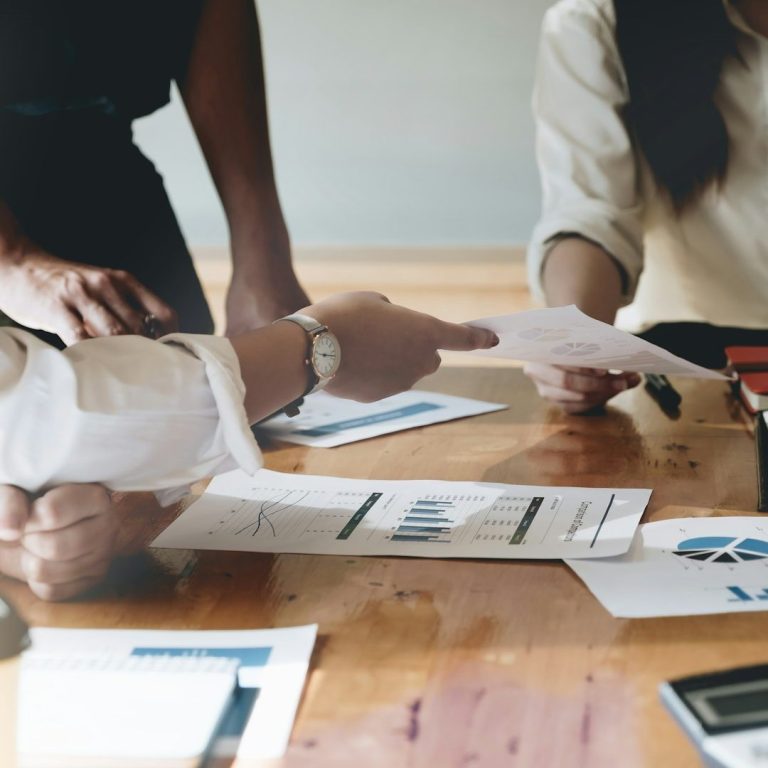 Personnes discutant autour d'une table, avec des documents et des graphiques. Personnes discutant autour d'une table, avec des documents et des graphiques.