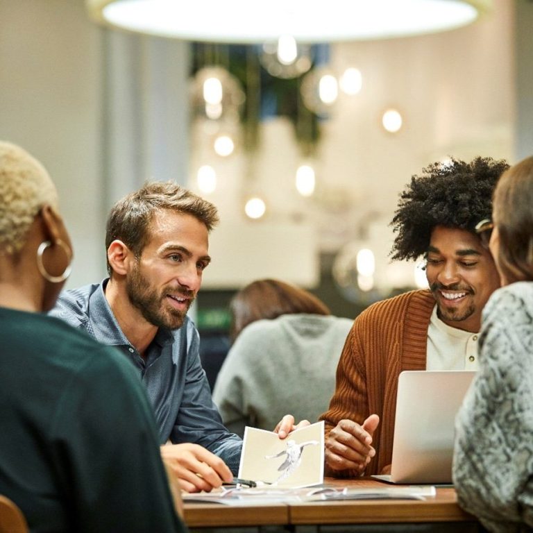 Un groupe de personnes échange des idées autour d'une table dans un café animé. Un groupe de personnes échange des idées autour d'une table dans un café animé.